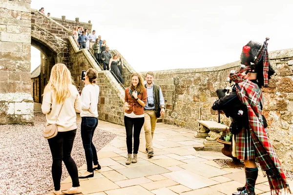 people outside in front of man with bag pipes